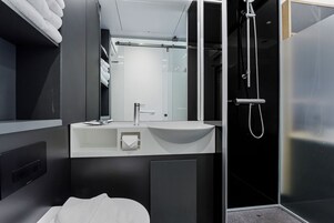 A modern bathroom with a white sink, mirror, and shower.