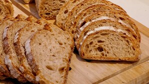 A loaf of sliced bread on a wooden cutting board with a window in the background. - The Z Hotel Trafalgar (London)