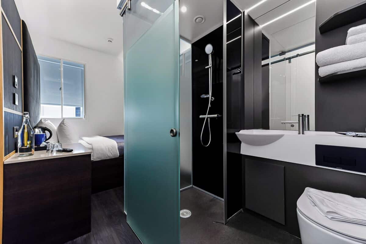 Une salle de bain moderne avec une douche à parois de verre, un lavabo blanc et un meuble-lavabo aux tons foncés.