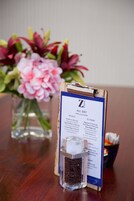 A menu board with a drink and a flower vase.