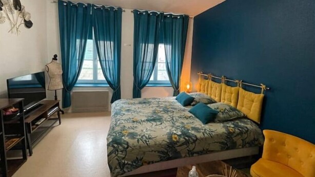 Ein Schlafzimmer mit Bett, Fernseher, Kommode und Stuhl.