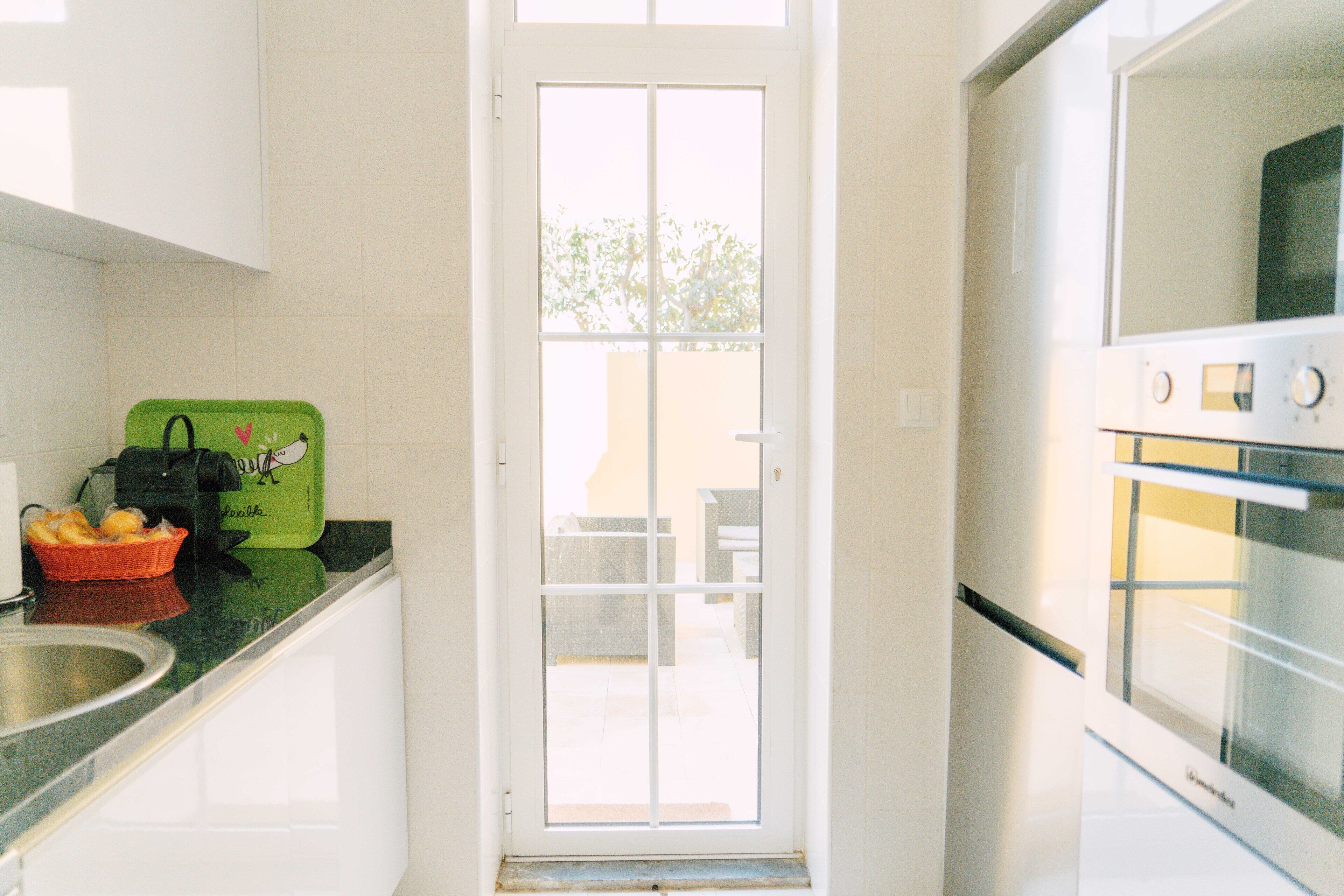 A kitchen with white cabinets, a green cutting board, and a stainless steel sink.