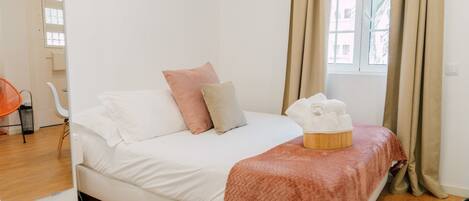 A bedroom with a bed, pillows, a blanket, and a window with curtains.