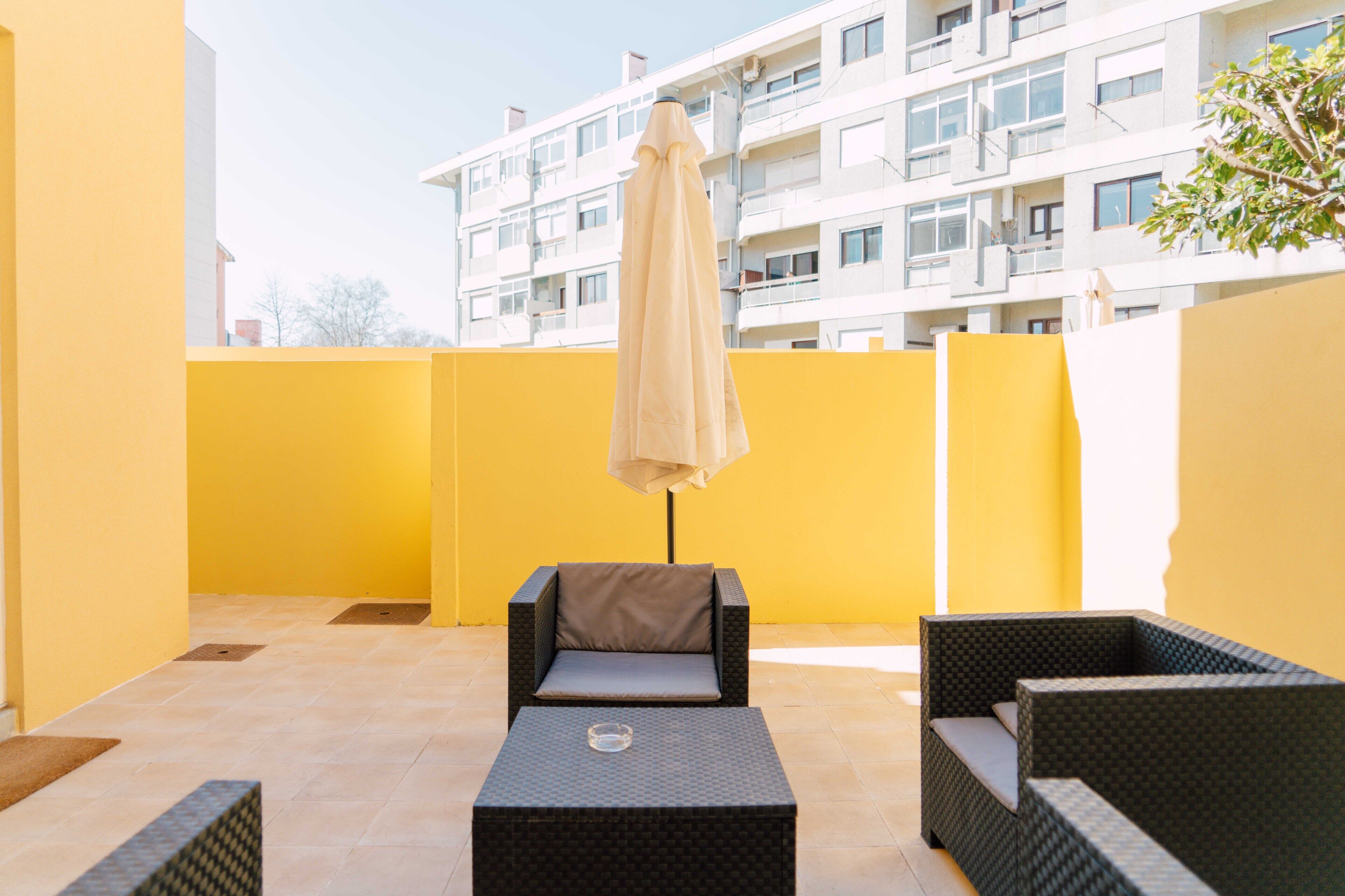 An outdoor patio with a sofa, a small table, and an umbrella.
