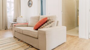 A living room with a beige sofa, a patterned throw pillow, a striped rug, and a white coffee table. - Oporto Yellow Villas   (Porto)