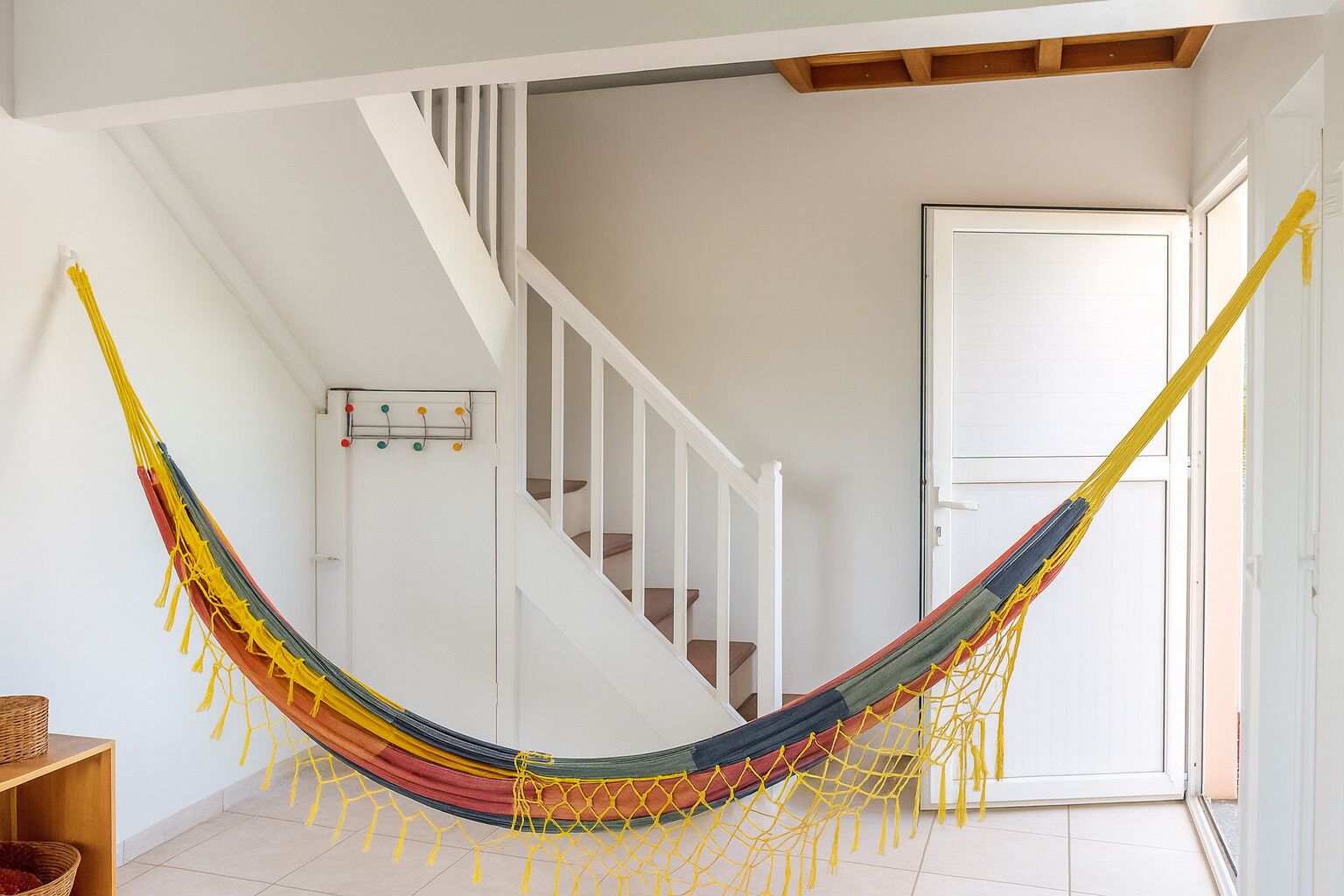 A hammock in a room with a staircase and a door.