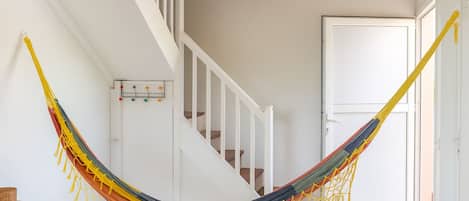 A hammock in a room with a staircase and a door.