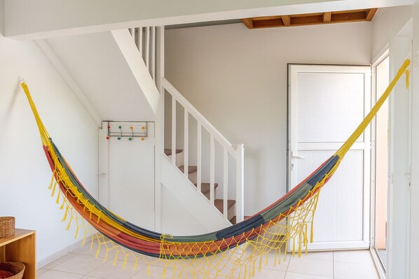 A hammock in a room with a staircase and a door.