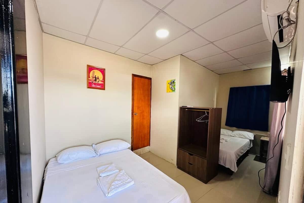 Een hotelkamer met een eenpersoonsbed, een kledingkast, een bureau en een klein tafeltje.