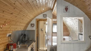 A compact, wooden interior with a kitchen, a shower, and a bed.