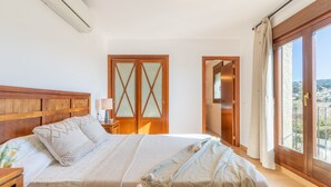 A bedroom with a wooden headboard, a bed with a patterned bedspread, a nightstand with a lamp, and a large window with a view. - Villa Isabel by Sun & Sea Homes (Moraira)