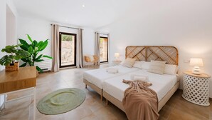 A bedroom with a bed, bedside tables, a chair, and a potted plant. - Villa S'airieta - Finca-Style Villa with Private Gardens Near Playa de Muro (Mallorca)