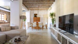 A spacious living area with a sofa, coffee table, dining table, chairs, and a TV.