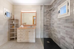 Un baño con tocador, espejo y ducha.