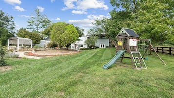 Ein Garten mit Spielhaus, Rutsche und überdachter Sitzgruppe.