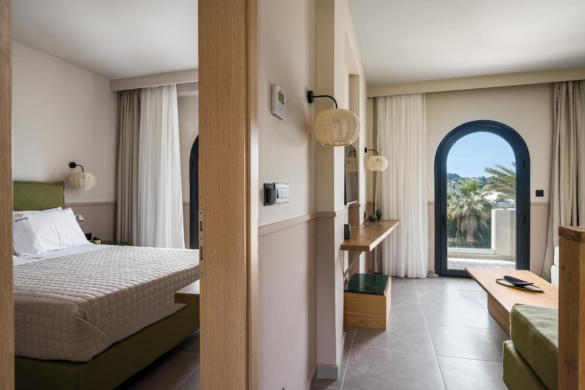 Ein Hotelzimmer mit Bett, Schreibtisch, Stuhl, Fenster mit Aussicht und einer Tür.