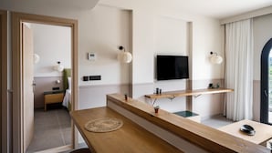 A modern hotel room with a wooden reception desk, a flat-screen TV mounted on the wall, and a small shelf with decorative items. - Loadstar Rooms & Suites  (Corfu)