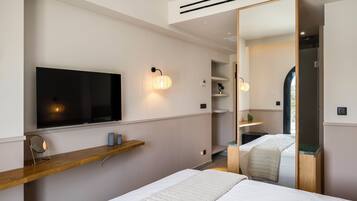 Una camera da letto moderna con un letto grande, una TV a parete, uno scaffale in legno e uno specchio.