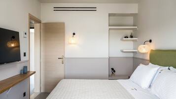 A modern bedroom with a bed, bedside tables, a TV, and wall-mounted shelves.