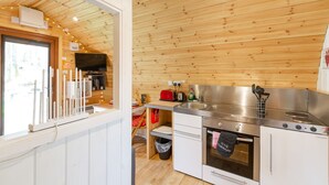 A modern kitchen with wooden ceiling, stainless steel appliances, and a window overlooking a garden. - Wee Oak Tree Luxury Lodge with private hot tub (Drymen)