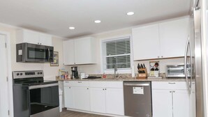 Una cocina moderna con armarios blancos, un refrigerador de acero inoxidable, un microondas y un lavavajillas.