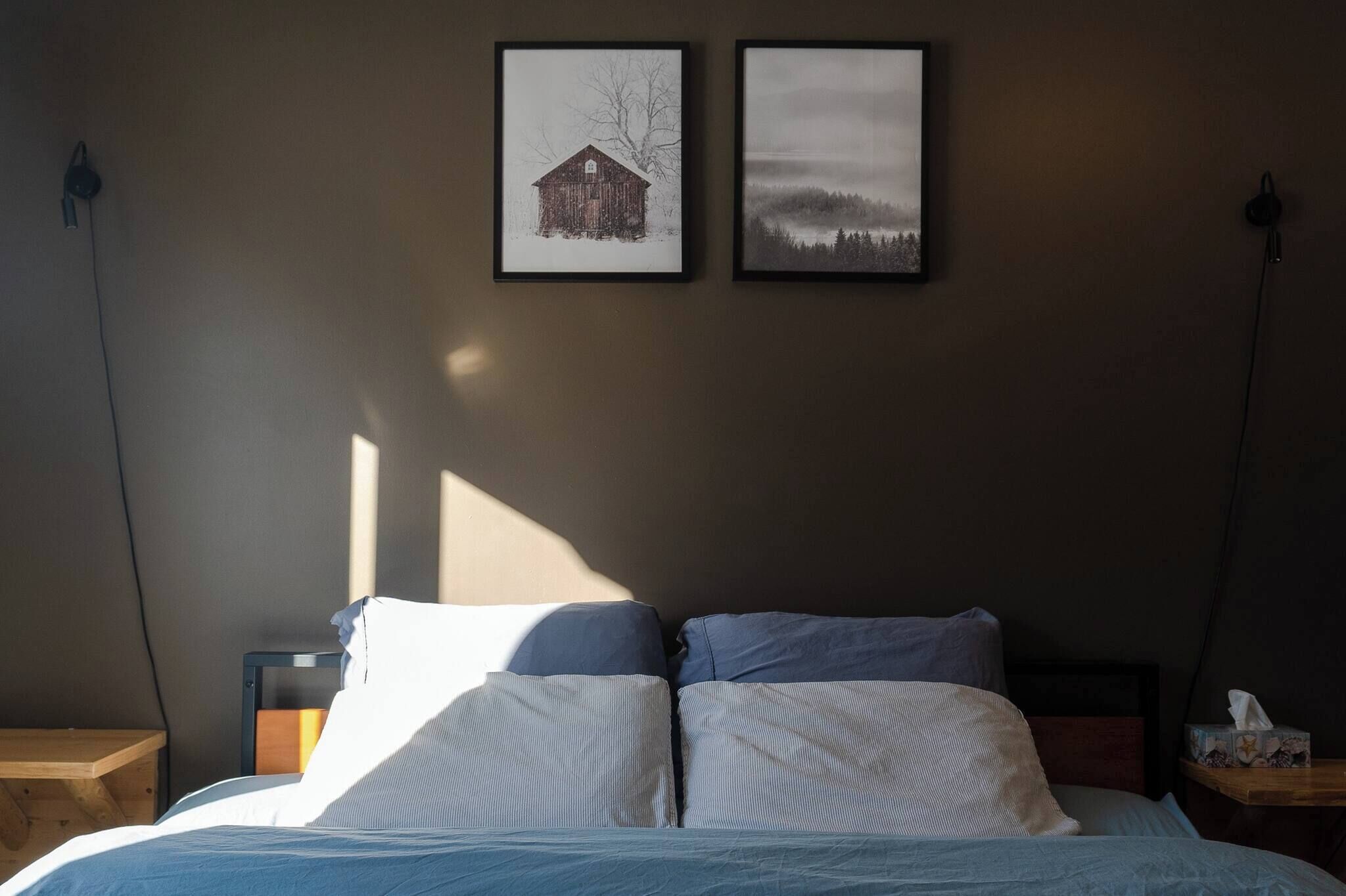Una cama con ropa de cama a rayas, una mesita de noche y dos cuadros en la pared.