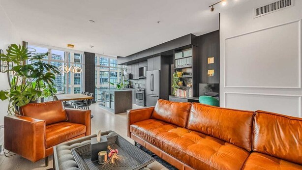 Uma sala de estar moderna com sofás de couro, uma mesa de centro e uma área de jantar com vista para a cidade.