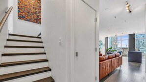 Interior moderno com escada, sofá e vista para prédios.
