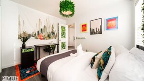 Un dormitorio moderno con una cama, un escritorio y una lámpara colgante verde.