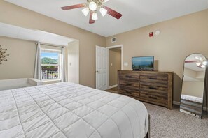 A bedroom with a bed, a dresser, a television, a ceiling fan, and a window with a view. - Wake Up to the River, Walk to the Fun - 3 BR Condo (Pigeon Forge)