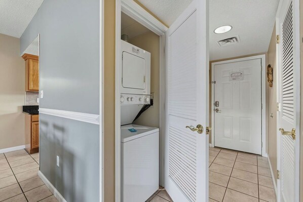 A laundry room with a washer and dryer, a door with a brass handle, and a tiled floor. - Wake Up to the River, Walk to the Fun - 3 BR Condo (Pigeon Forge)