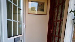 A narrow hallway with a white door, a brown welcome mat, and a framed picture on the wall. - Impeccable 1-bed Lodge in Eastleigh (Eastleigh)