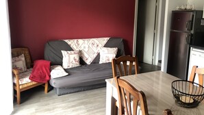 Ein Wohnzimmer mit einem dunkelgrauen Sofa, einem Holzesstisch und einer weißen Dekoration von einem Hirschkopf an der Wand.