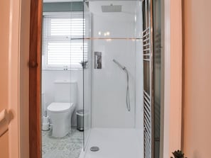 A modern bathroom with a glass-enclosed shower, a toilet, and a sink.