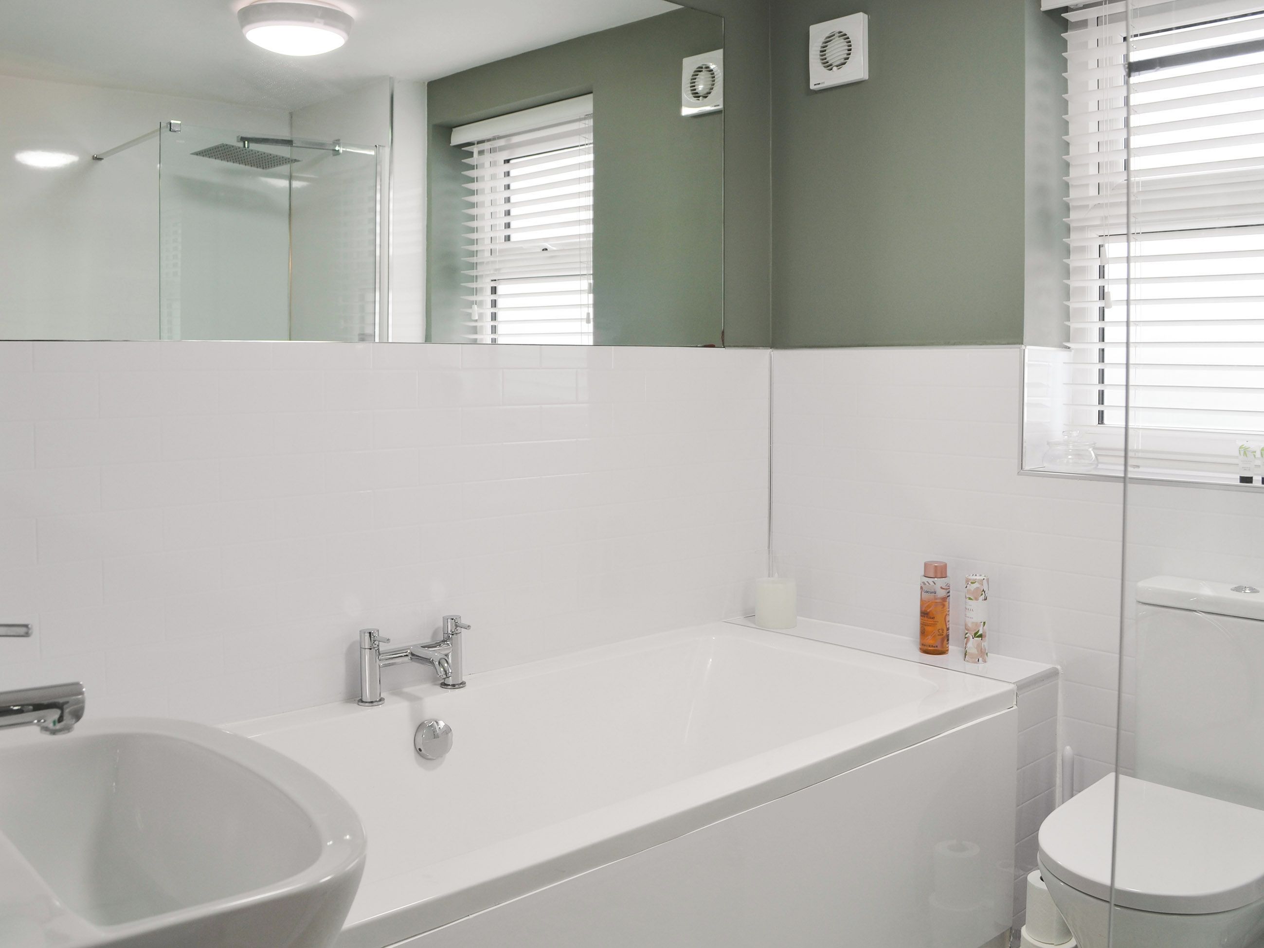 A bathroom with a bathtub, a sink, a toilet, and a mirror.