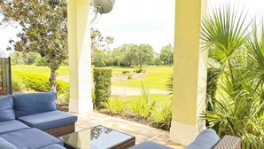 A covered outdoor seating area with a view of a golf course. - RR7510 – Luxury 6BR Villa w/ Pool, Hot Tub & Game Room on Reunion Golf Course (Kissimmee)
