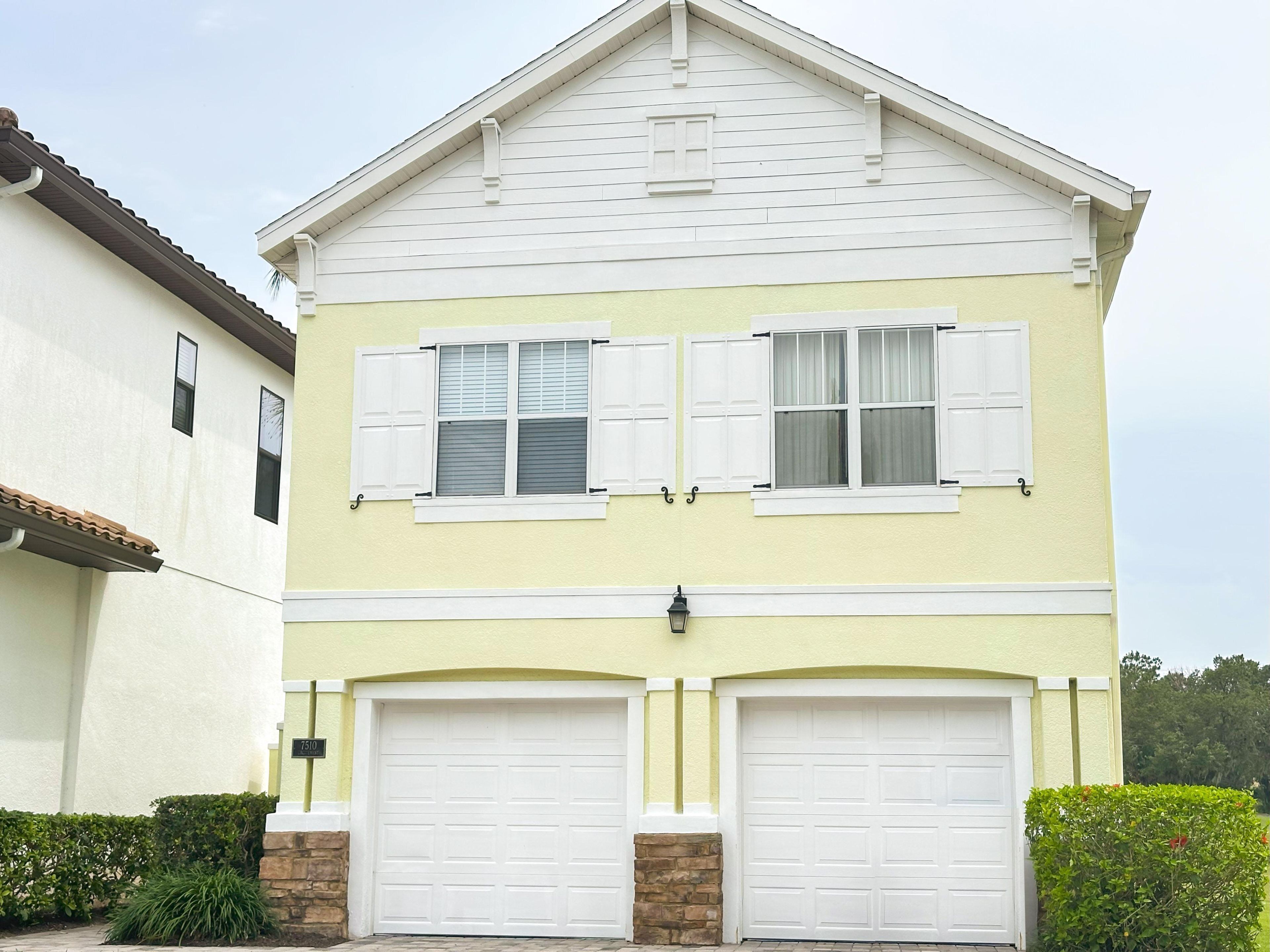 A two-story house with a gabled roof, white shutters, and two garage doors.
