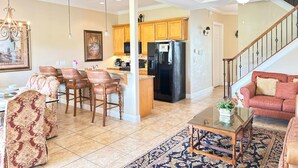 A spacious living area with a dining table, chairs, a sofa, and a kitchen in the background. - RR7510 – Luxury 6BR Villa w/ Pool, Hot Tub & Game Room on Reunion Golf Course (Kissimmee)