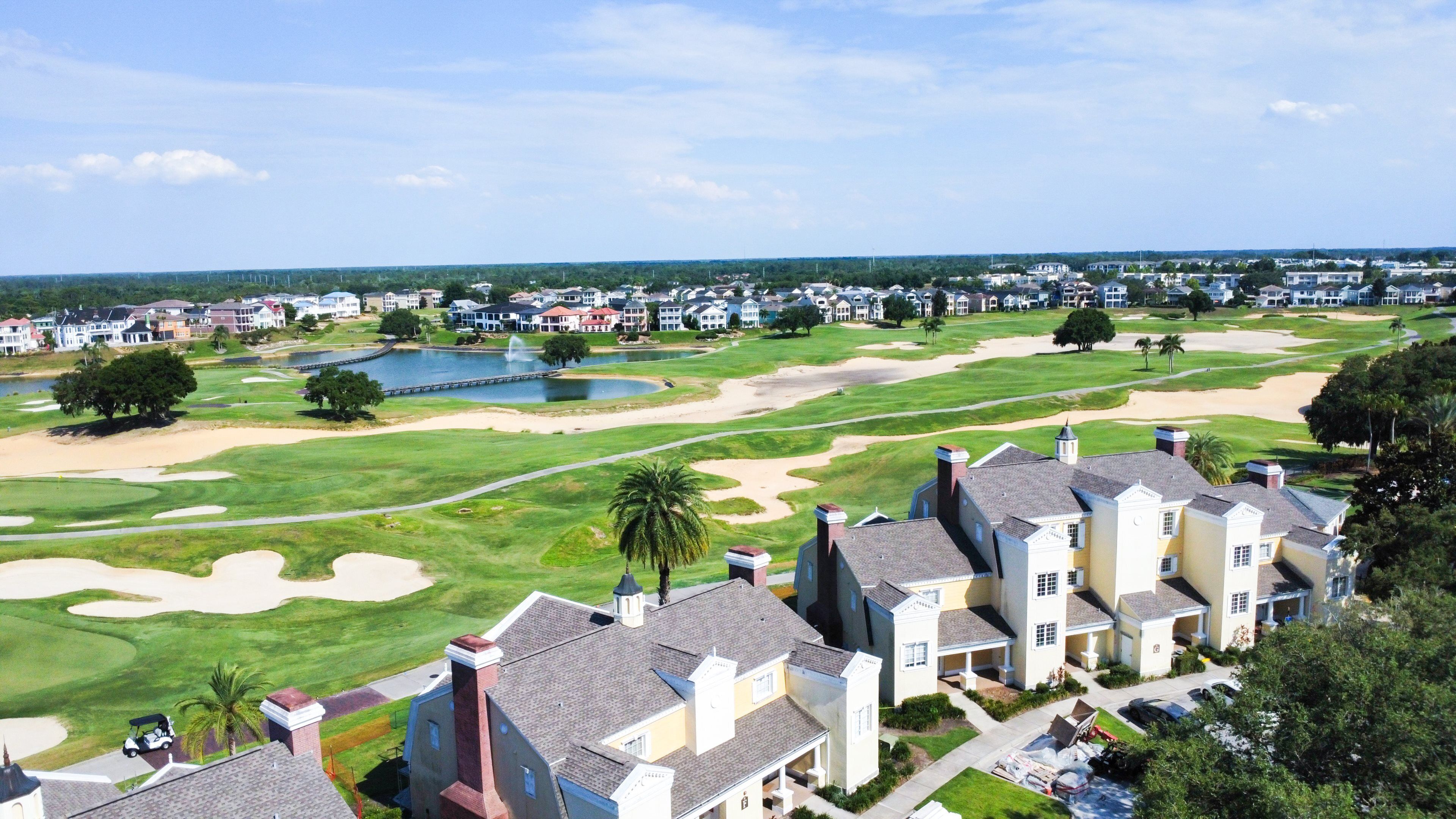 Un campo da golf con bunker di sabbia, uno stagno e un club house.