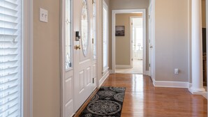 A hallway with wooden flooring, white doors, and a patterned rug.
