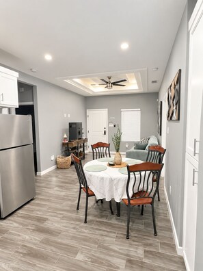 A modern kitchen with a built-in refrigerator, a dining area with a round table and chairs, and a ceiling fan.