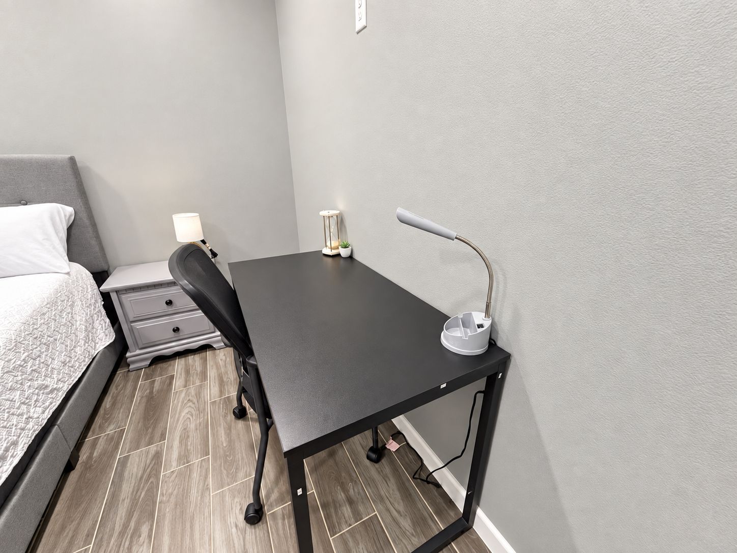 A small, modern bedroom with a bed, a desk, and a chair.