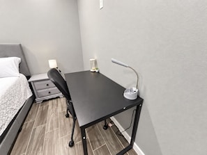 A small, modern bedroom with a bed, a desk, and a chair. - Modern 3BR Apartment (San Juan)