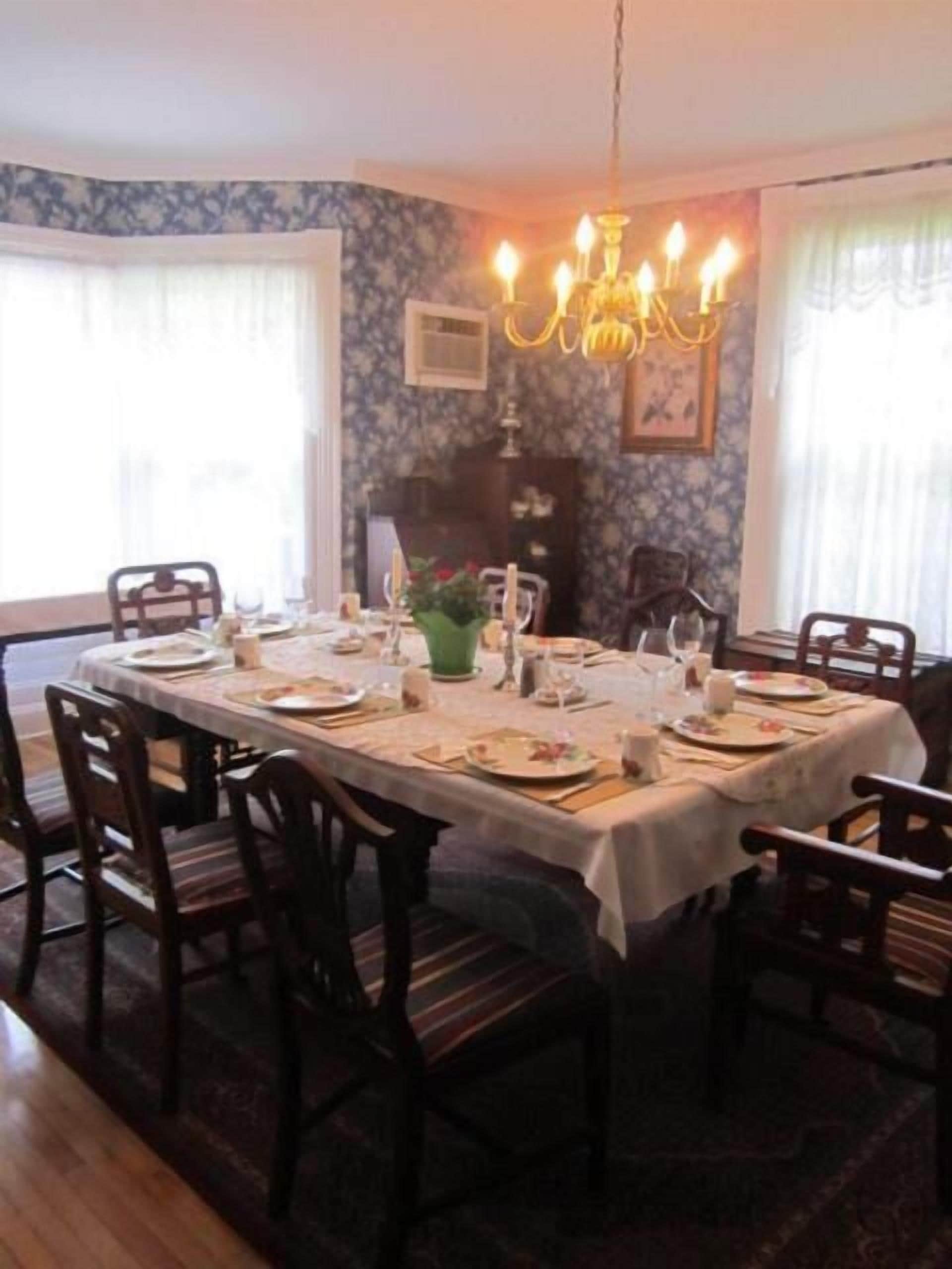 A dining room with a large table set for a meal, surrounded by chairs.