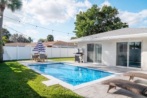 Ein Garten mit Swimmingpool, Grill und Gartenmöbeln.