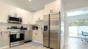 Een moderne keuken met roestvrijstalen apparatuur, licht houten keukenkastjes en een groot raam met uitzicht op de omgeving.