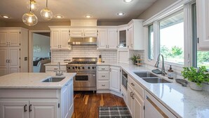 A modern kitchen with white cabinetry, stainless steel appliances, and pendant lighting. - Lakeview Luxury - Deck With View, 3 Family Rooms (Manhattan)
