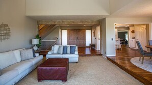 A spacious living area with a high ceiling, a staircase, and a view to the upper floor. - Lakeview Luxury - Deck With View, 3 Family Rooms (Manhattan)