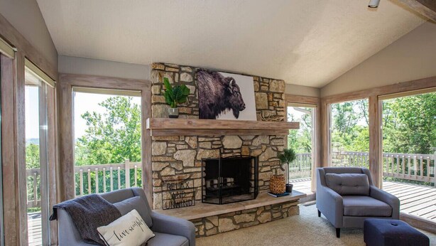A cozy living room with a stone fireplace, two gray sofas, and a large window overlooking a deck. - Lakeview Luxury - Deck With View, 3 Family Rooms (Manhattan)