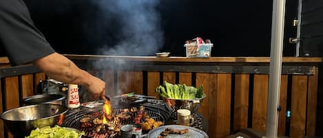 Una parrilla con diferentes carnes y verduras cocinándose.